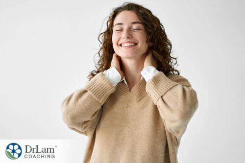 An image of a smiling woman with both hands at the back of her head