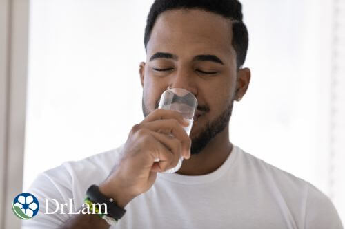 A man drinks distilled water from a clear glass