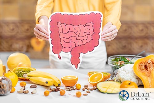 Diet is central An image of a woman holding a picture of the gut with healthy whole foods around her on a table
