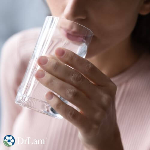 A woman sips distilled water from a glass