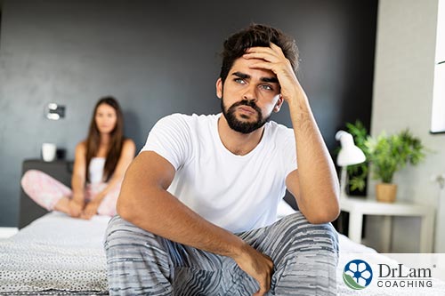 An image of a frustrated man and woman sitting on their bed