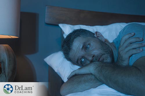An image of a depressed man laying in bed unable to sleep