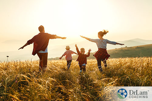 An image of a family running through a field with their arms out playing airplane