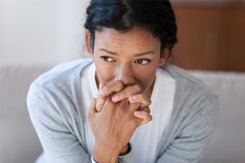 An image of a woman sitting down with her fingers clasped